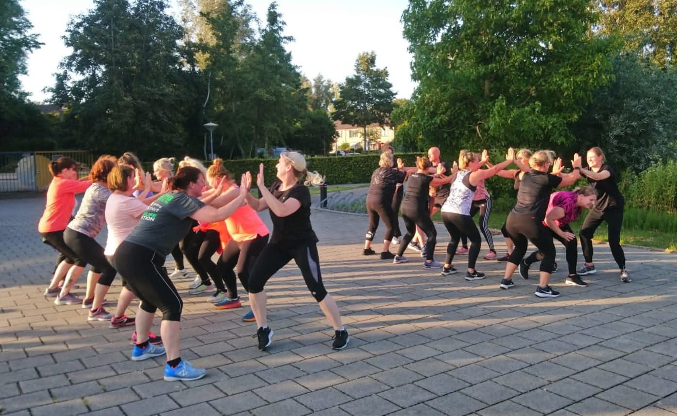 Groep doet een duwoefening in tweetallen tijdens de FitCamp